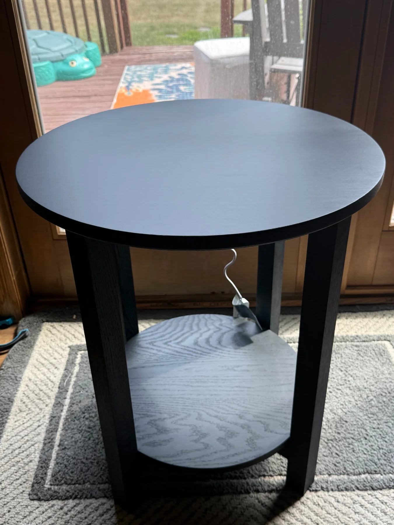 Black round table with a lower shelf and bold dark finish